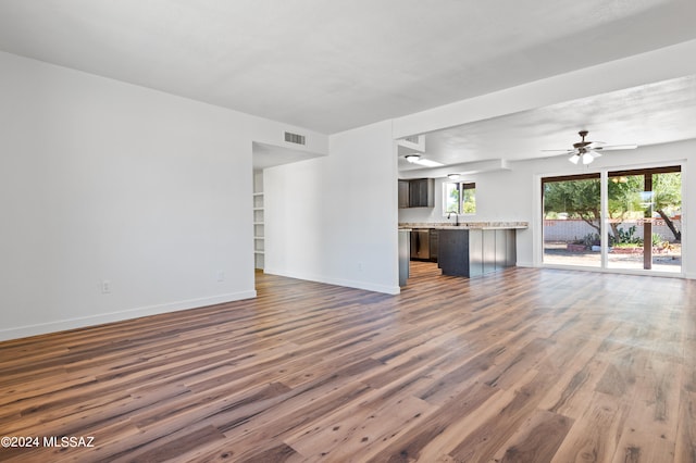 unfurnished living room featuring ceiling fan, dark wood-type flooring, and sink