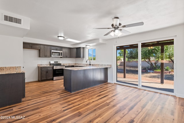 kitchen featuring dark brown cabinets, appliances with stainless steel finishes, kitchen peninsula, and light hardwood / wood-style flooring