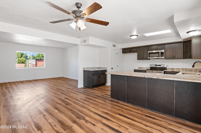 kitchen featuring ceiling fan, sink, kitchen peninsula, appliances with stainless steel finishes, and hardwood / wood-style floors