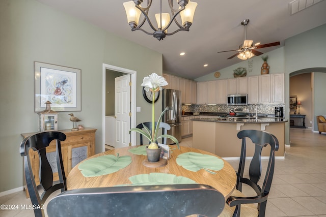 dining space featuring ceiling fan with notable chandelier, sink, light tile patterned floors, and vaulted ceiling