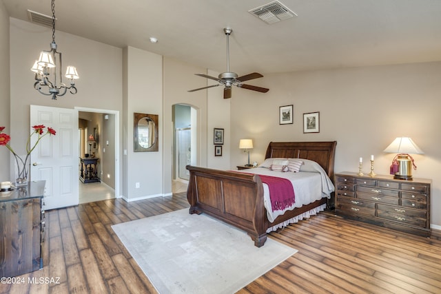 bedroom with high vaulted ceiling, ceiling fan with notable chandelier, and hardwood / wood-style flooring