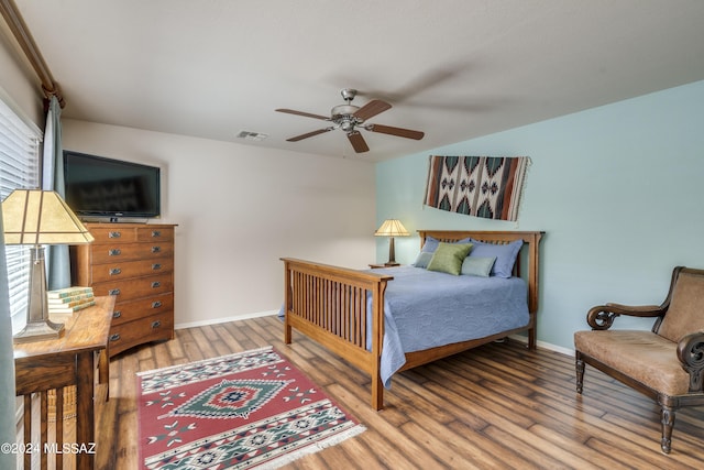 bedroom featuring multiple windows, wood-type flooring, and ceiling fan