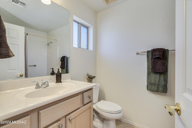 bathroom featuring tile patterned flooring, vanity, toilet, and walk in shower