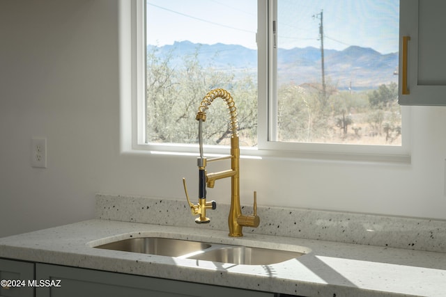 details with a mountain view, sink, and light stone counters