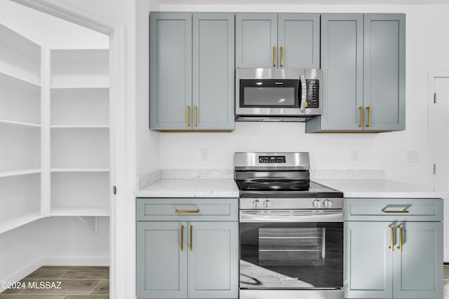 kitchen featuring light stone countertops, appliances with stainless steel finishes, and gray cabinets