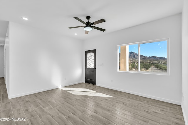 unfurnished room featuring a mountain view, light hardwood / wood-style floors, and ceiling fan