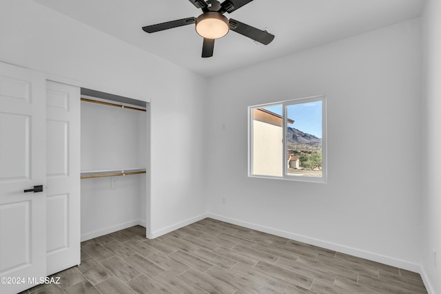 unfurnished bedroom with light wood-type flooring, ceiling fan, and a closet