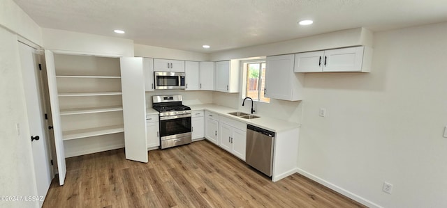 kitchen featuring white cabinets, sink, a textured ceiling, appliances with stainless steel finishes, and light wood-type flooring