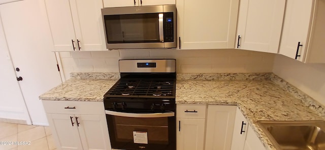 kitchen with appliances with stainless steel finishes, decorative backsplash, light stone countertops, and white cabinets