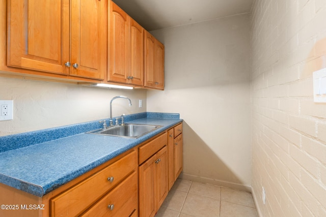 kitchen featuring light tile patterned floors, sink, and brick wall