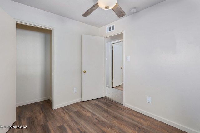 unfurnished bedroom with ceiling fan and dark wood-type flooring