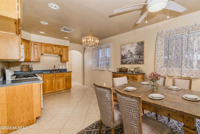 kitchen featuring stove, ceiling fan with notable chandelier, sink, hanging light fixtures, and light tile patterned flooring