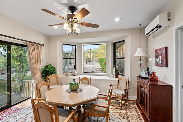 dining room featuring a healthy amount of sunlight, wood-type flooring, a wall mounted AC, and ceiling fan