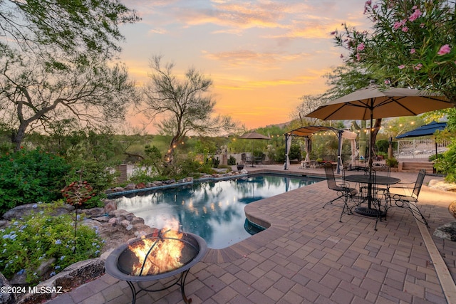 pool at dusk featuring a patio