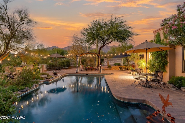 pool at dusk with a mountain view and a patio area