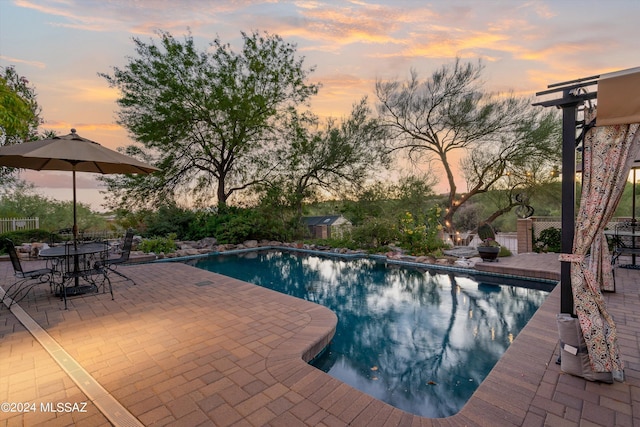 pool at dusk featuring a patio area and an outdoor pool