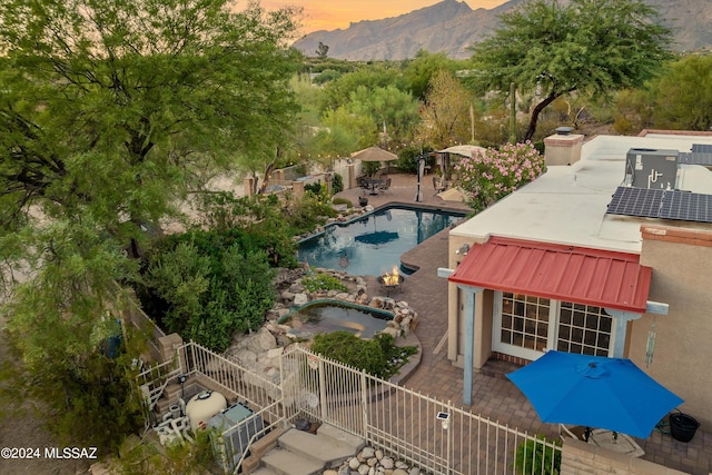 pool at dusk featuring a jacuzzi and a patio