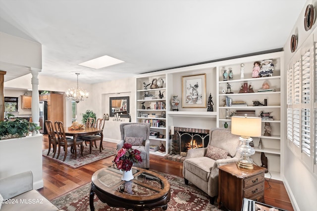 living room with a brick fireplace, a notable chandelier, and hardwood / wood-style floors