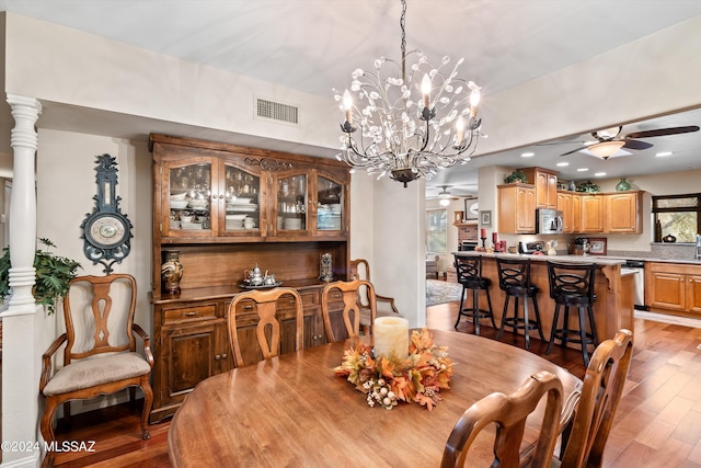 dining room featuring ceiling fan with notable chandelier, light hardwood / wood-style floors, and ornate columns