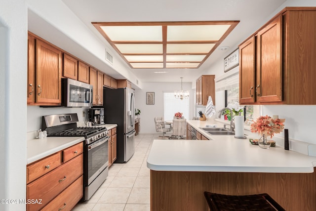 kitchen featuring appliances with stainless steel finishes, kitchen peninsula, pendant lighting, sink, and a chandelier