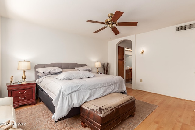 bedroom featuring light hardwood / wood-style floors, ensuite bathroom, and ceiling fan