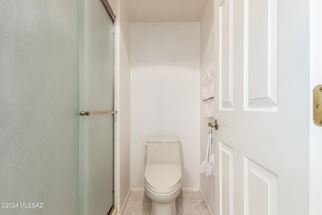 bathroom with tile patterned floors, a shower with shower door, and toilet