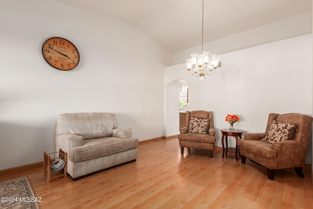 living area with an inviting chandelier, lofted ceiling, and hardwood / wood-style floors