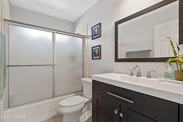 full bathroom featuring shower / bath combination with glass door, vanity, and toilet