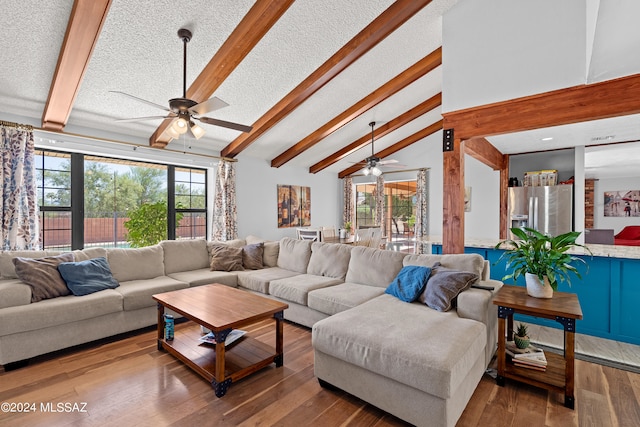 living room featuring a textured ceiling, wood-type flooring, beamed ceiling, and ceiling fan