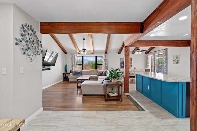 living room with light hardwood / wood-style flooring, vaulted ceiling with beams, ceiling fan, and a healthy amount of sunlight