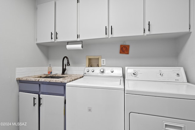 laundry room with cabinet space, washer and dryer, and a sink