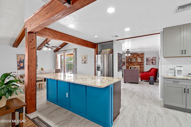 kitchen featuring stainless steel fridge, lofted ceiling with beams, a center island, and ceiling fan