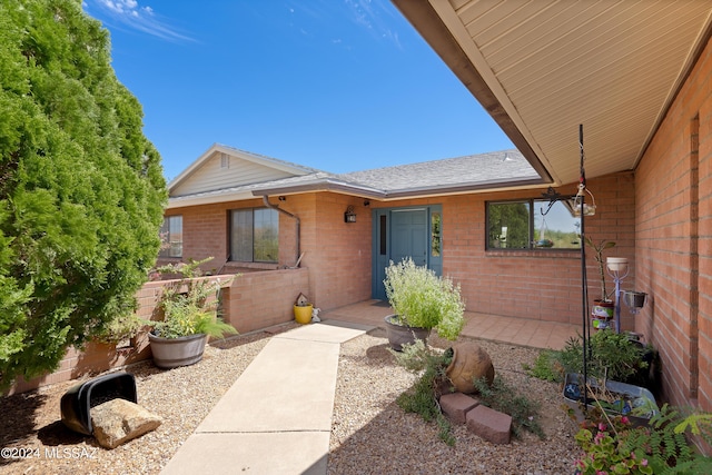 property entrance with brick siding and roof with shingles