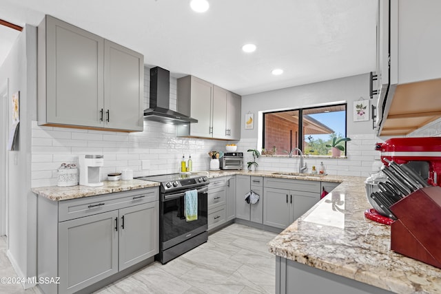 kitchen featuring sink, electric range oven, wall chimney range hood, gray cabinets, and decorative backsplash