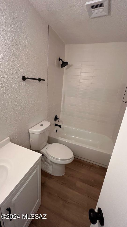 full bathroom with wood-type flooring, tiled shower / bath combo, vanity, and toilet