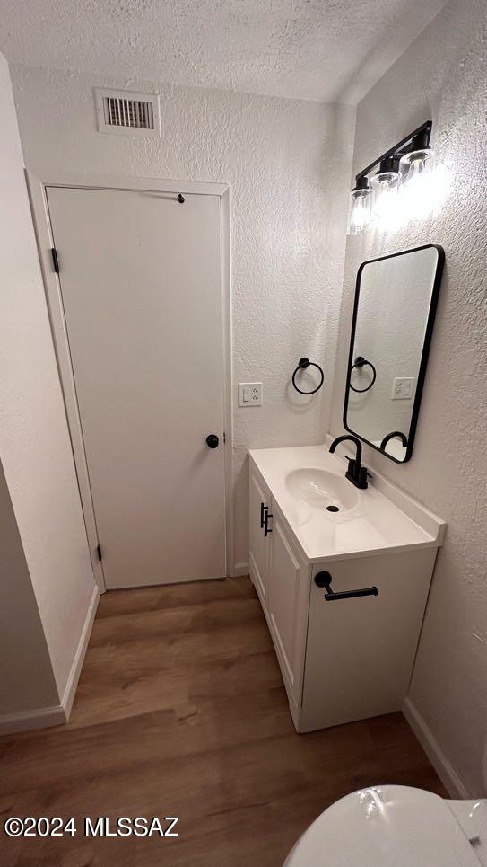 bathroom with a textured ceiling, toilet, vanity, and hardwood / wood-style floors