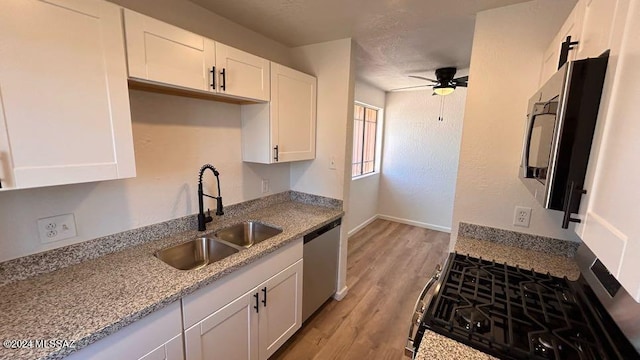 kitchen with ceiling fan, sink, stainless steel dishwasher, light hardwood / wood-style flooring, and white cabinetry