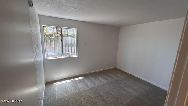 unfurnished room with dark colored carpet and a textured ceiling