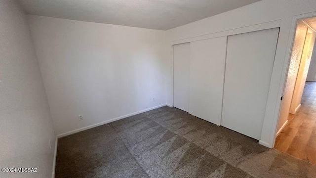 unfurnished bedroom with dark carpet and a closet