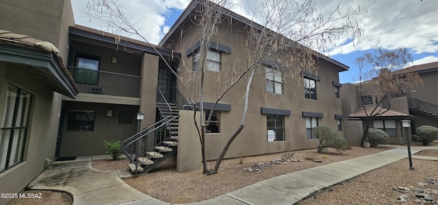 view of side of home with stairway and stucco siding