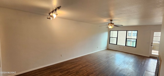 empty room featuring a textured ceiling, dark wood-type flooring, ceiling fan, and track lighting