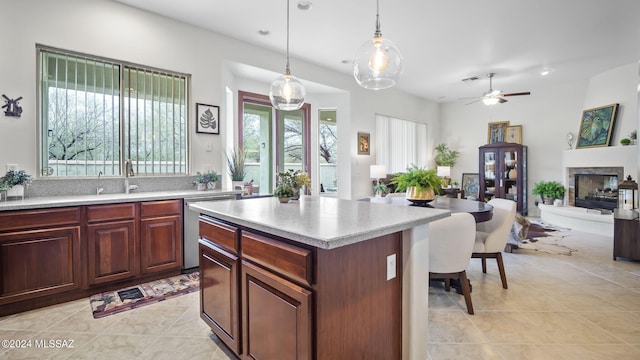 kitchen with hanging light fixtures, a center island, ceiling fan, stainless steel dishwasher, and sink