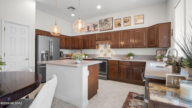 kitchen with hanging light fixtures, sink, stainless steel appliances, a center island, and a towering ceiling