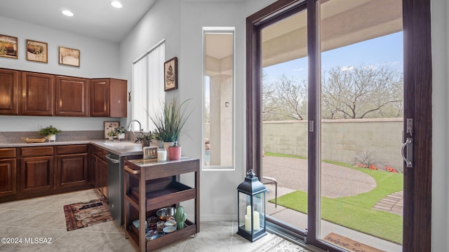 kitchen featuring stainless steel dishwasher, sink, and light tile patterned floors