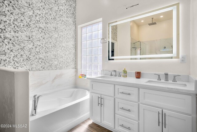 bathroom with plus walk in shower, hardwood / wood-style floors, and vanity