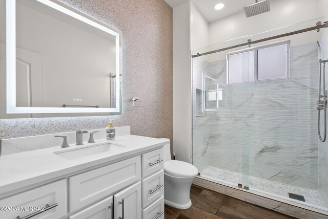 bathroom featuring wood-type flooring, vanity, a shower with shower door, and toilet