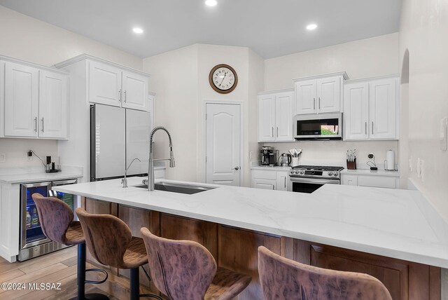 kitchen featuring white cabinets, appliances with stainless steel finishes, light hardwood / wood-style flooring, and a breakfast bar