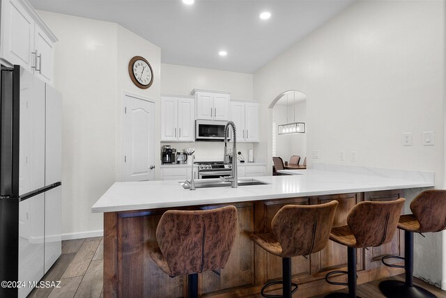 kitchen featuring kitchen peninsula, dark wood-type flooring, stainless steel appliances, and white cabinets