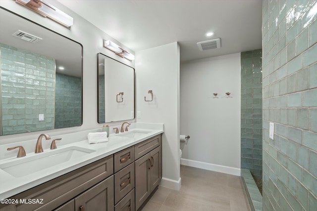 bathroom featuring toilet, a tile shower, vanity, and tile patterned floors