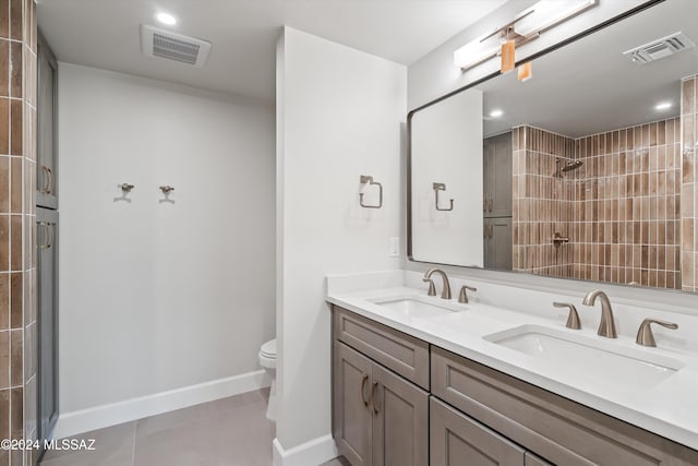 bathroom featuring toilet, a tile shower, vanity, and tile patterned floors